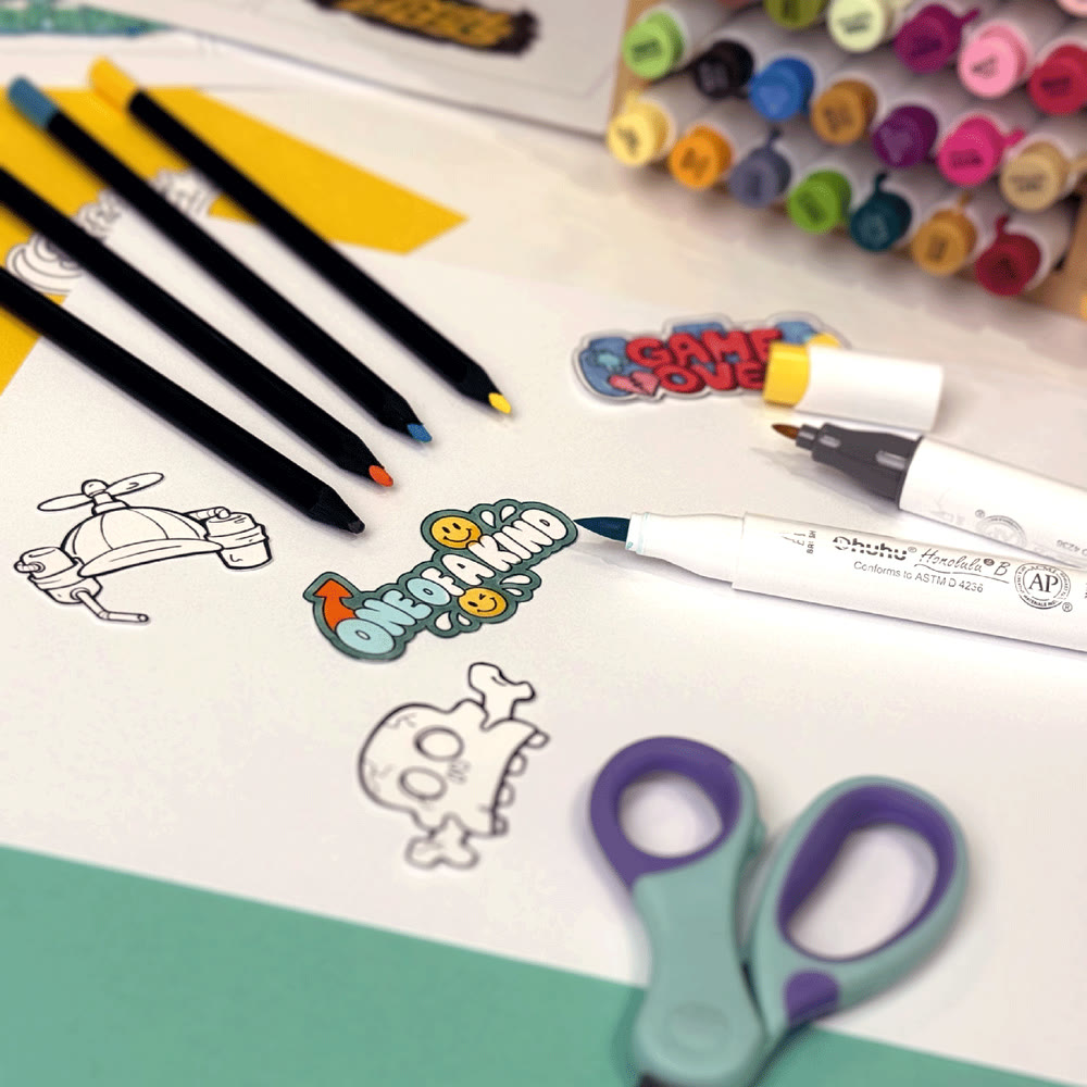 Markers, scissors and a coloured sticker on a sticker-making work table